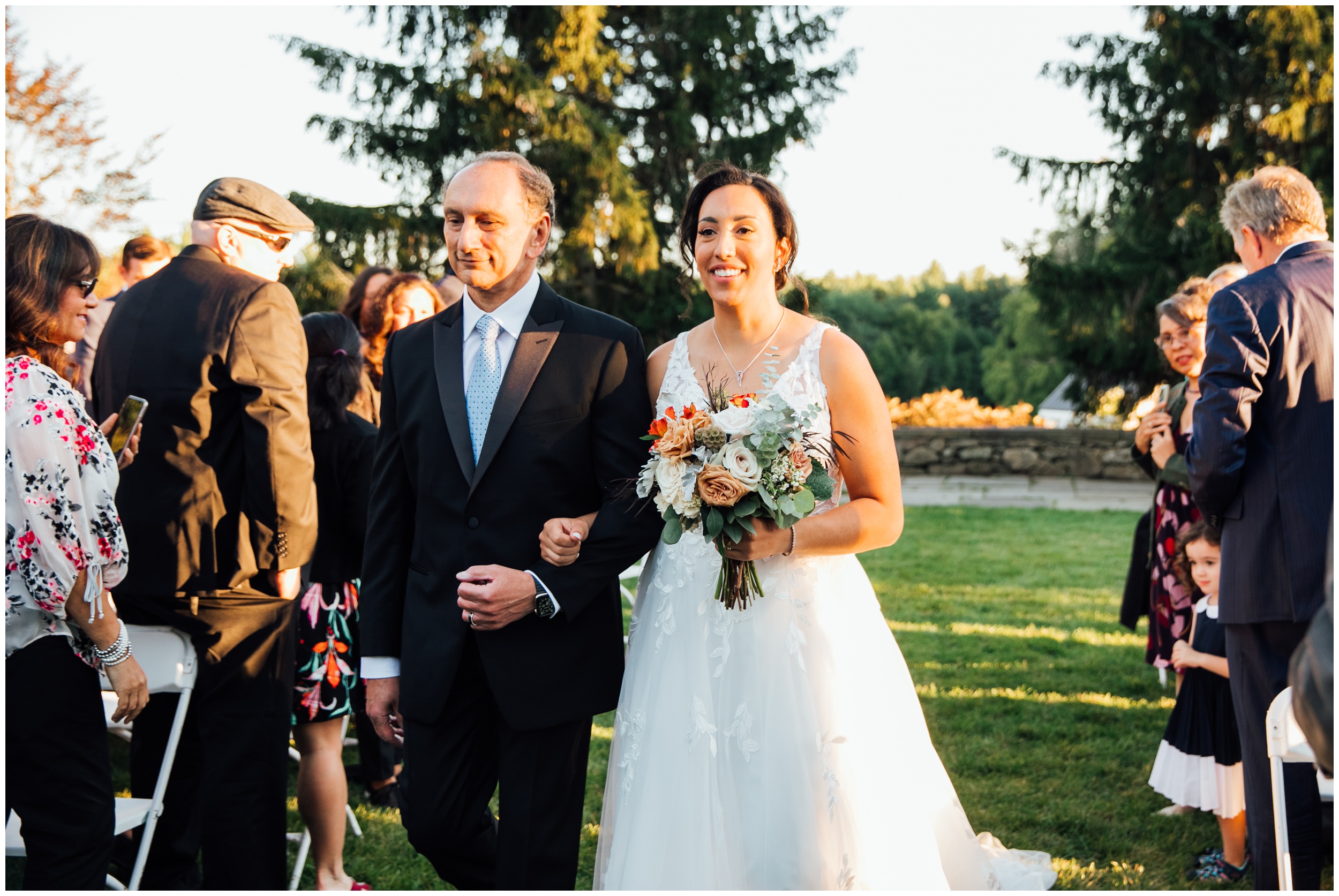 Bride walking with her father during outdoor ceremony at New England Botanic Garden at Tower Hill in Massachusetts